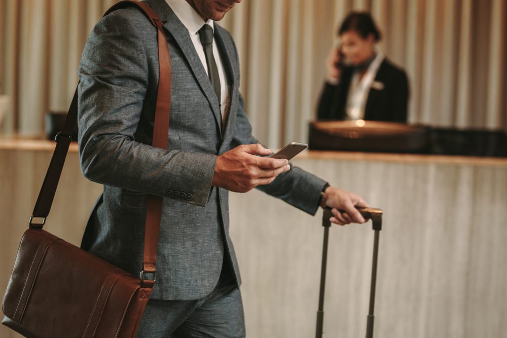 hotel-check-in-guest-phone hotel guest walking away from check in counter looking at phone